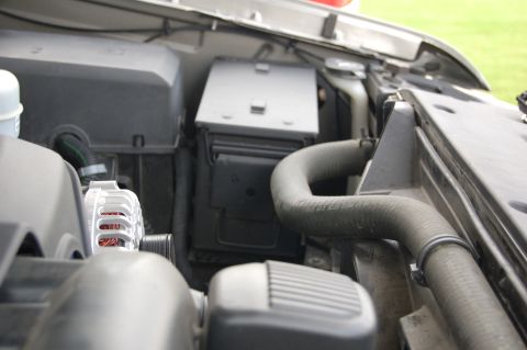 2007 Chevrolet Silverado 1500 - The engine bay of a 2007 Chevrolet Silverado 1500, a close-up view of the fuse box and a prominent radiator hose.