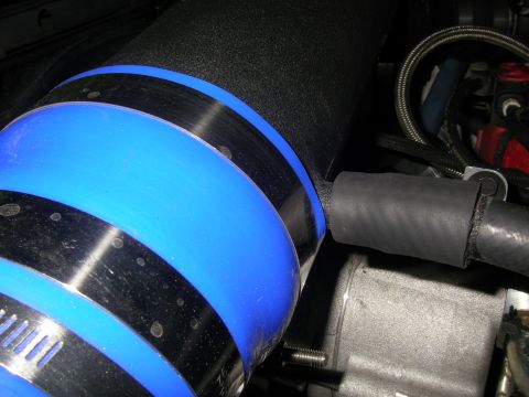1990 Ford Bronco - Close-up of an aftermarket intake tube with blue accents and metal hose clamps, likely part of a vehicle's engine system.