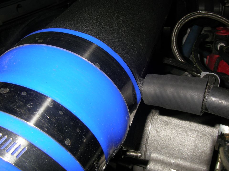 Blue and black intake tube with metal clamps in engine bay