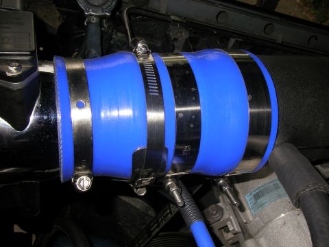 1990 Ford Bronco - Close-up of a blue silicone intake hose with metal clamps, likely in a vehicle's engine bay.
