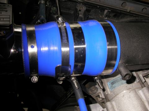 1990 Ford Bronco - Close-up of a blue silicone hose and metal clamps on an engine component.