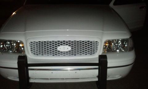 1998 Ford Crown Victoria - Front view of a white 1998 Ford Crown Victoria, its distinctive grille and headlights, with a push bar installed.