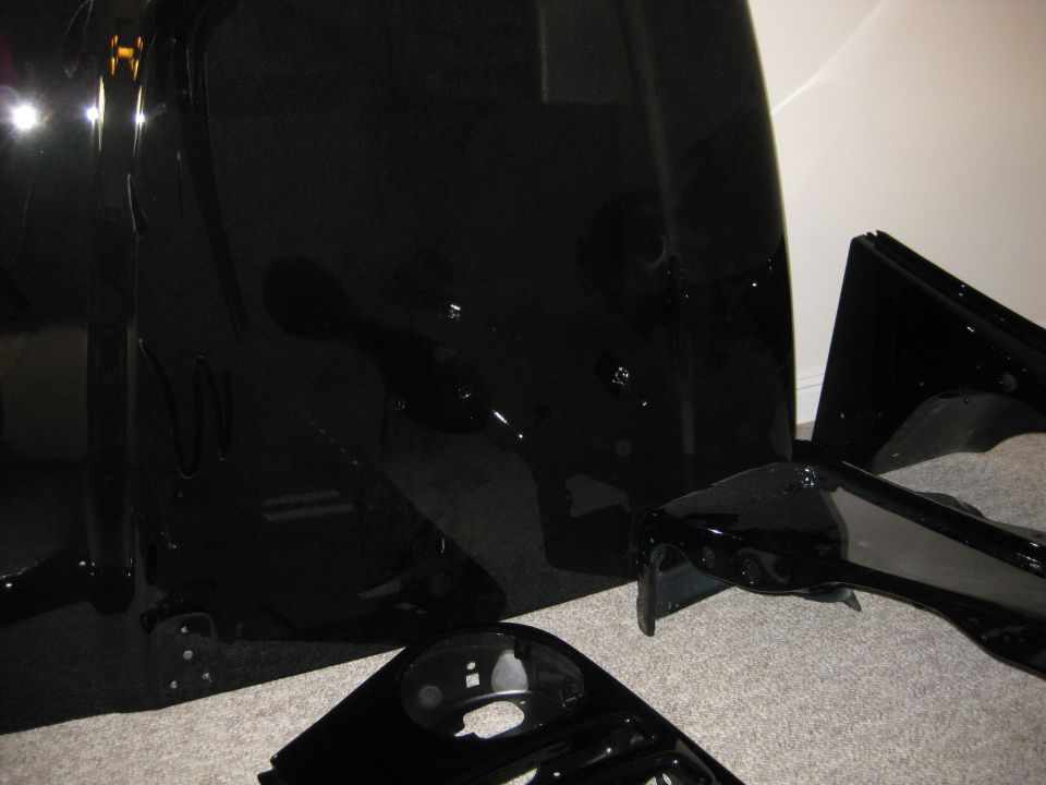 black car body panels laid out on a carpeted floor