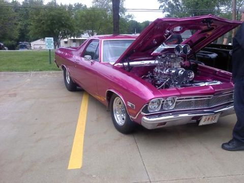 1970 Ford Ranchero - A heavily modified pickup truck with an exposed engine and a vibrant pink paint job is parked outdoors.