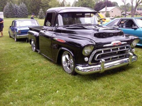 1970 Ford Ranchero - A black Chevrolet pickup truck is parked on a grassy field next to other vehicles.