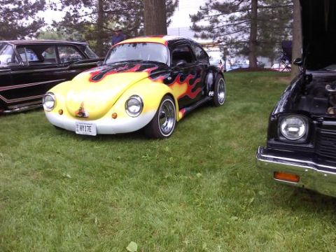 1970 Ford Ranchero - Customized Volkswagen Beetle with flame paint job sits on display next to other vehicles.