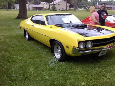 1970 Ford Ranchero - A yellow muscle car is parked on a grassy lawn with two people standing nearby.