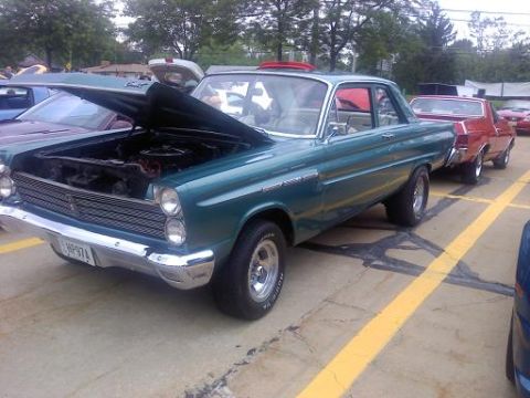 1970 Ford Ranchero - A teal 1964 Mercury Comet is parked with its hood up, alongside other vehicles.