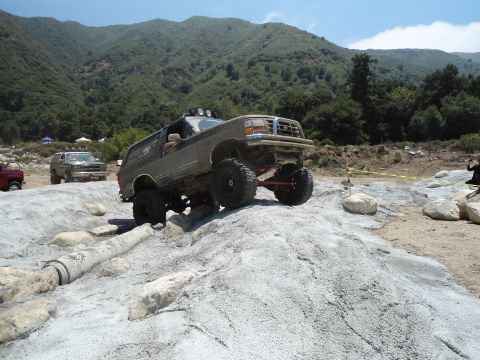 1994 Ford Bronco - A modified 1995 Ford Bronco navigates a challenging off-road course with other vehicles visible in the background.