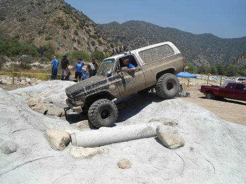 1994 Ford Bronco - Off-road SUV navigates a rocky obstacle course, with spectators and another vehicle present.