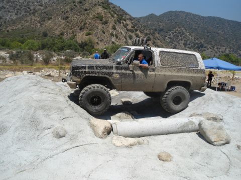 1994 Ford Bronco - This SUV is covered in mud while attempting to traverse a challenging off-road terrain.