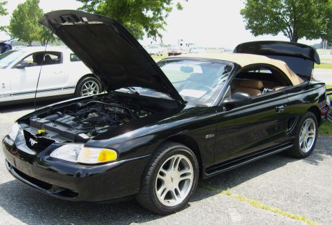 2007 Ford Mustang - A black convertible Mustang is parked with its hood open, revealing the engine bay.