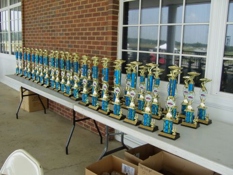 2007 Ford Mustang - Numerous trophies are lined up on tables outside a building, awaiting distribution.