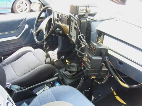 2007 Ford Mustang - The interior of a vehicle equipped with police radio and other gear, complete with handcuffs on the steering column.