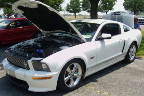 2007 Ford Mustang - A white 2007 Ford Mustang GT is displayed with its hood open, revealing the engine compartment.