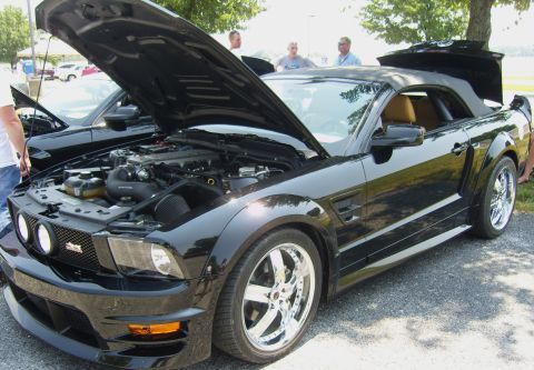 2007 Ford Mustang - A black 2007 Ford Mustang convertible is displayed with its hood open, revealing the engine bay. Another Mustang is visible behind it.