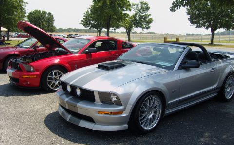 2007 Ford Mustang - Two Ford Mustangs, a silver convertible and a red coupe, are parked side-by-side at an outdoor event.