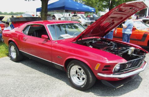 2007 Ford Mustang - Red 1970 Ford Mustang Mach 1 at a car show, hood open, with another vehicle visible.