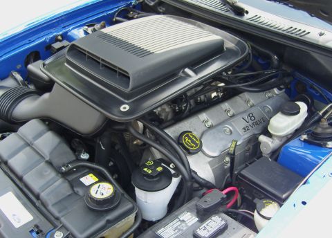 2007 Ford Mustang - The engine bay of a blue Ford Mustang shows a V8 32 valve engine with a prominent air intake system.