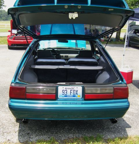 2007 Ford Mustang - Rear view of a teal 1993 Ford Mustang hatchback with its trunk open. A red car is visible in the background.