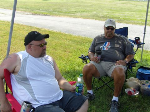 2007 Ford Mustang - Two men relax outdoors under a canopy, with drinks and coolers nearby.