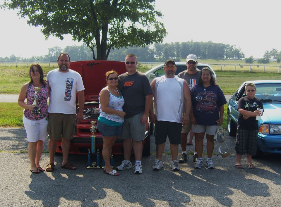Group posing with red car and blue car