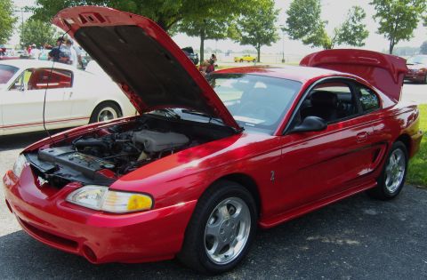 2007 Ford Mustang - A red Ford Mustang is parked outside with its hood and trunk open, showing the engine and cargo space.