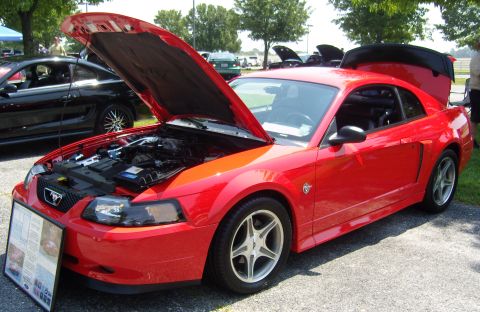 2007 Ford Mustang - A red Ford Mustang is displayed with its hood and trunk open, revealing the engine and interior. A display board is placed in front of the…