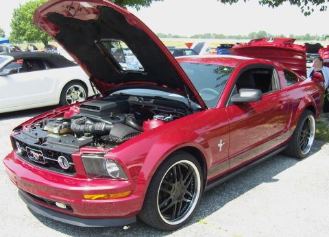 2007 Ford Mustang - Red 2007 Ford Mustang coupe with hood open at an outdoor car show.