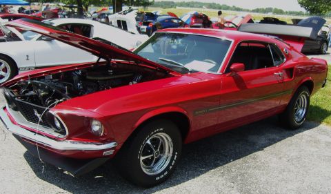 2007 Ford Mustang - Red 1969 Ford Mustang Mach 1 at a car show, hood open, with other vehicles visible.