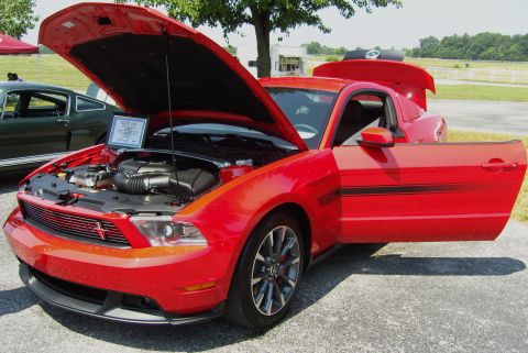 2007 Ford Mustang - A red Ford Mustang GT is displayed with its hood and driver's door open, revealing the engine compartment and interior.