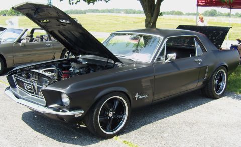 2007 Ford Mustang - A matte black 1967 Ford Mustang coupe is displayed with its hood and trunk open, parked next to another Mustang.