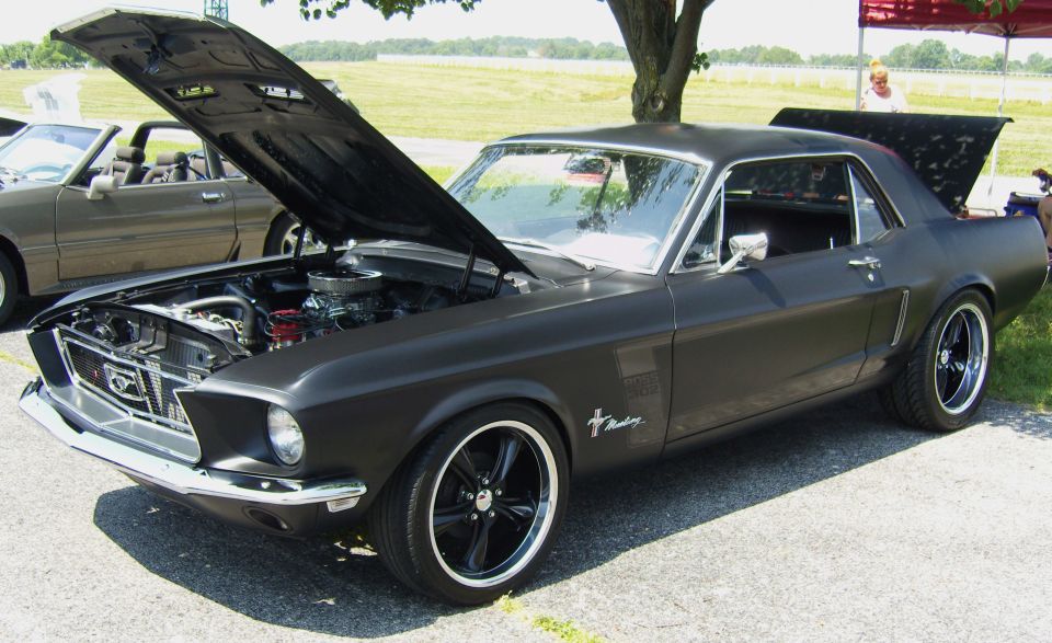Black 1967 Ford Mustang coupe with hood and trunk open, custom wheels, matte finish