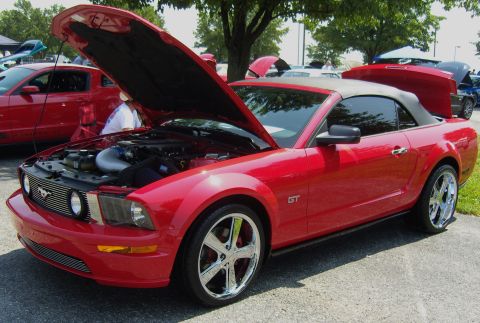 2007 Ford Mustang - A red 2007 Ford Mustang GT convertible is displayed with its hood open, revealing the engine bay.