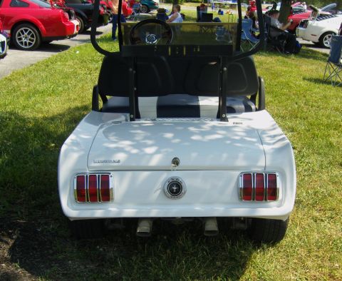 2007 Ford Mustang - A golf cart has been customized to resemble the rear of a classic car, complete with distinctive taillights and a Ford emblem.