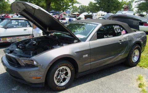 2007 Ford Mustang - A gray 2007 Ford Mustang convertible, modified for drag racing, is displayed with its hood open at a car show.