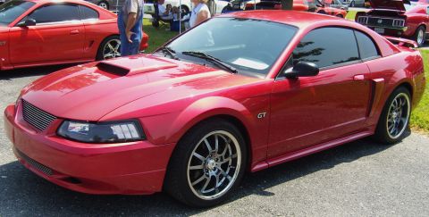 2007 Ford Mustang - A red Ford Mustang GT is parked at an outdoor event, with another Mustang visible behind it.