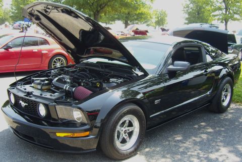 2007 Ford Mustang - A black 2007 Ford Mustang GT is displayed with its hood open, revealing the engine compartment.