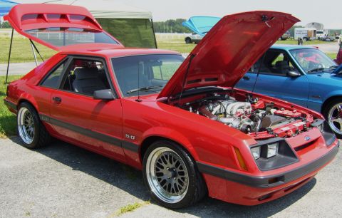 2007 Ford Mustang - A red 1987 Ford Mustang 5.0 is displayed with its hood and trunk open, revealing the engine and a rear spoiler.