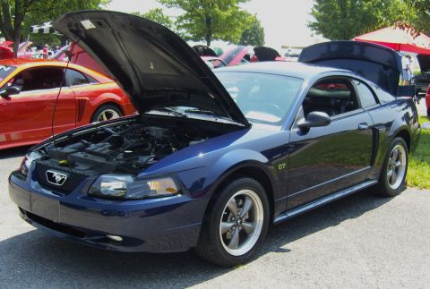 2007 Ford Mustang - A blue Ford Mustang GT is displayed with its hood open at an outdoor car show.