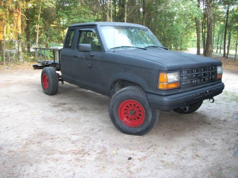 1994 Ford Explorer - This black pickup truck features red wheels and a modified bed, seen from a 3/4 front angle.