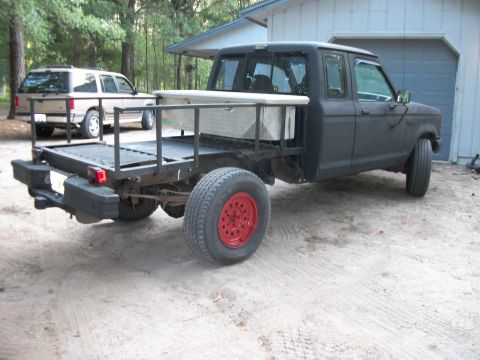 1994 Ford Explorer - Flatbed pickup truck with a toolbox and a tan SUV in the background.
