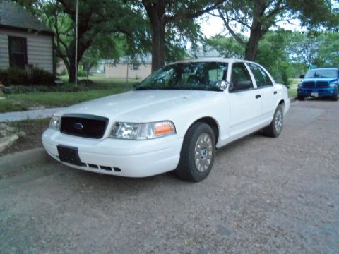 2000 Mercury Grand Marquis - A white sedan is parked on a street with a blue truck visible in the background.