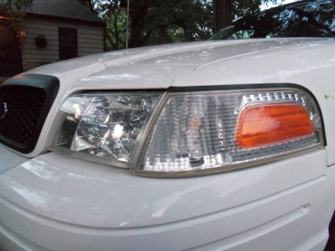 2000 Mercury Grand Marquis - Front corner view of a white 2000 Mercury Grand Marquis, showing the headlight and grille detail.