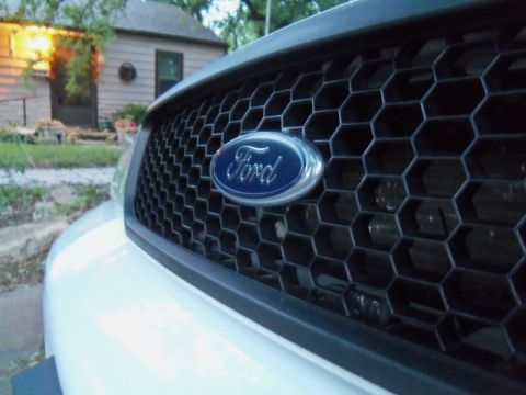 2000 Mercury Grand Marquis - Close-up of a white car's front grille the Ford logo and a honeycomb pattern.