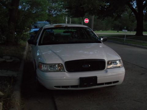 2000 Mercury Grand Marquis - White 2000 Ford Crown Victoria parked curbside with a stop sign in the background.