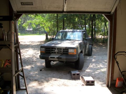 1994 Ford Explorer - Pickup truck with camouflage paint parked inside a garage with the door open.