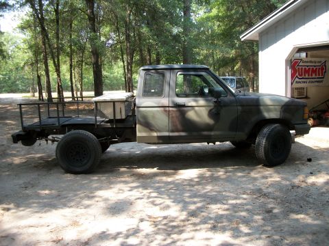1994 Ford Explorer - A camouflage flatbed truck is parked next to a garage with a Summit Racing Equipment banner.