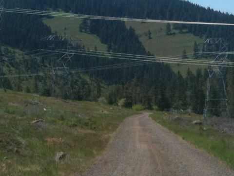 2005 Jeep Wrangler - A dirt road winds through a landscape dominated by power line infrastructure and forested hills.