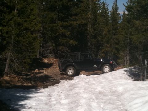 2005 Jeep Wrangler - A black Jeep Wrangler is parked on a snowy mountain road surrounded by pine trees.